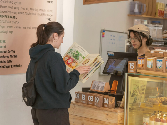 woman reading menu and waiting to be served in cafe