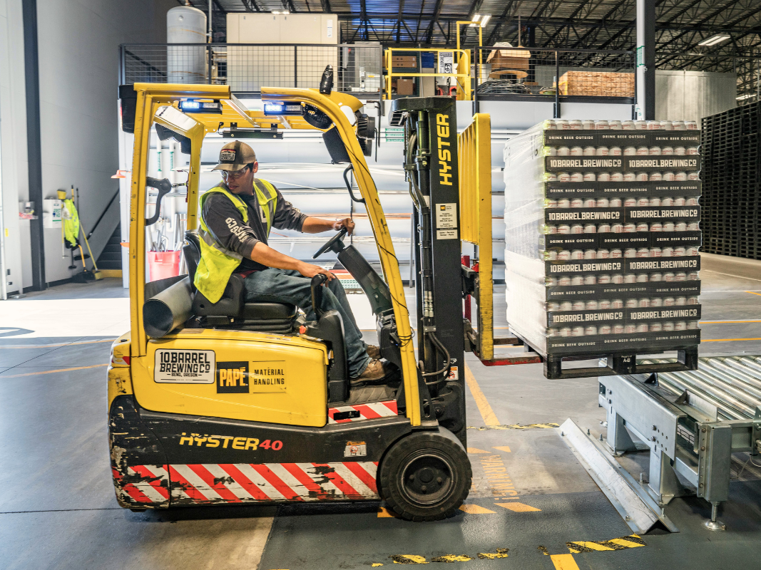 Man driving a pallet truck transporting beer in a warehouse